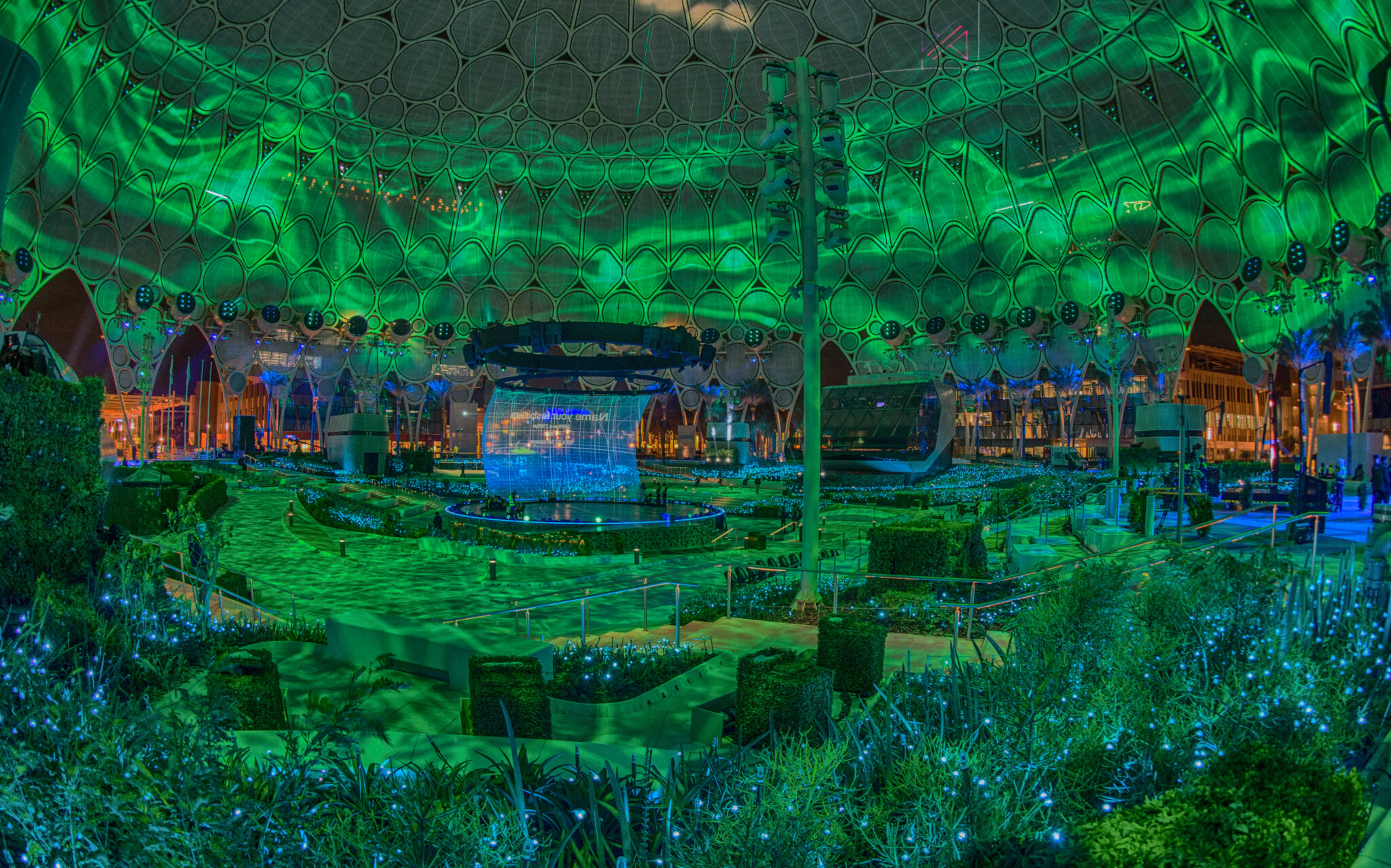 A domed arena interior washed in deep green projected light, the structure of the dome visible through the imagery.