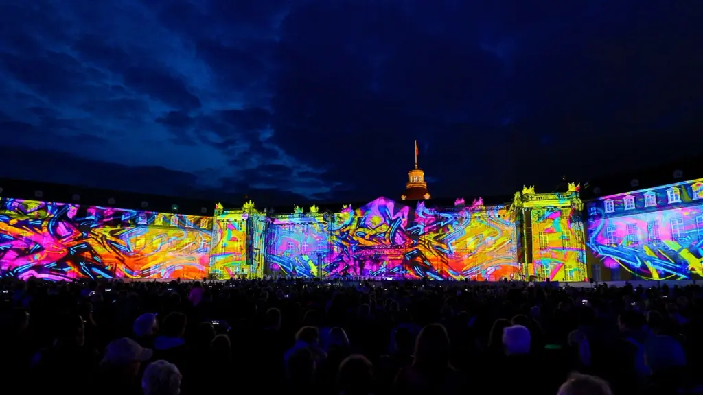 A large building illuminated with colorful abstract light projections during a nighttime event. BattleRoyalStudios