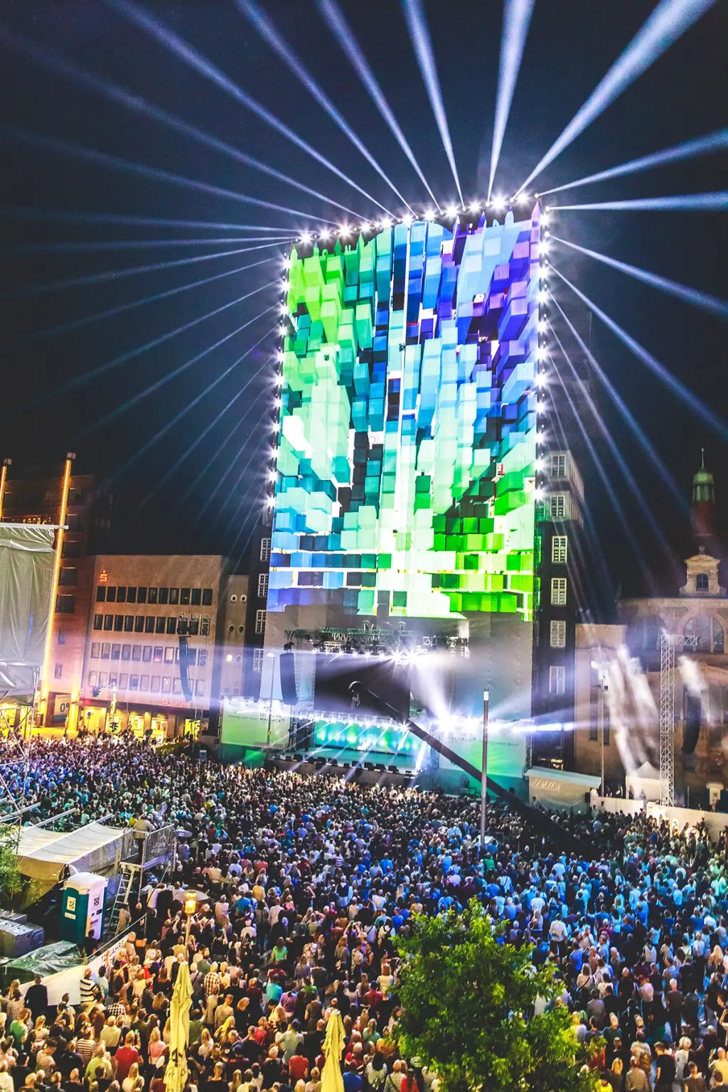 Projection mapping on a tall building during a large outdoor event, with a crowd gathered below. Battle Royal Studios