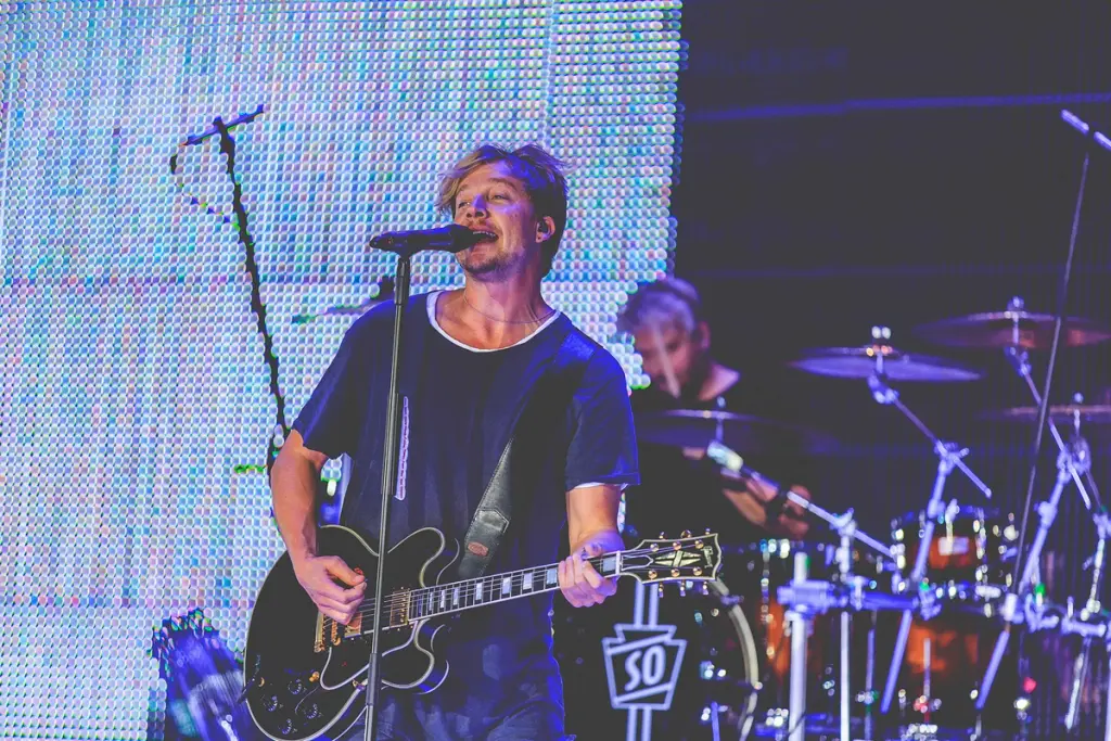 Lead singer playing guitar and singing into a microphone during a live performance at the BMW Festival. Battle Royal Studios