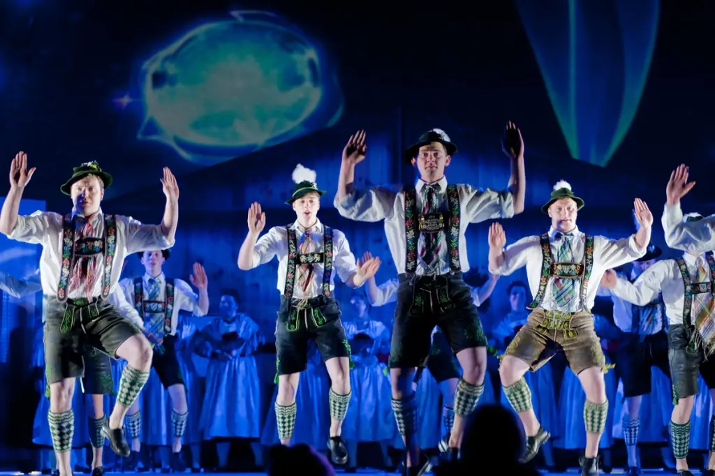 Men in traditional Bavarian attire performing a group dance on stage. BattleRoyalStudios