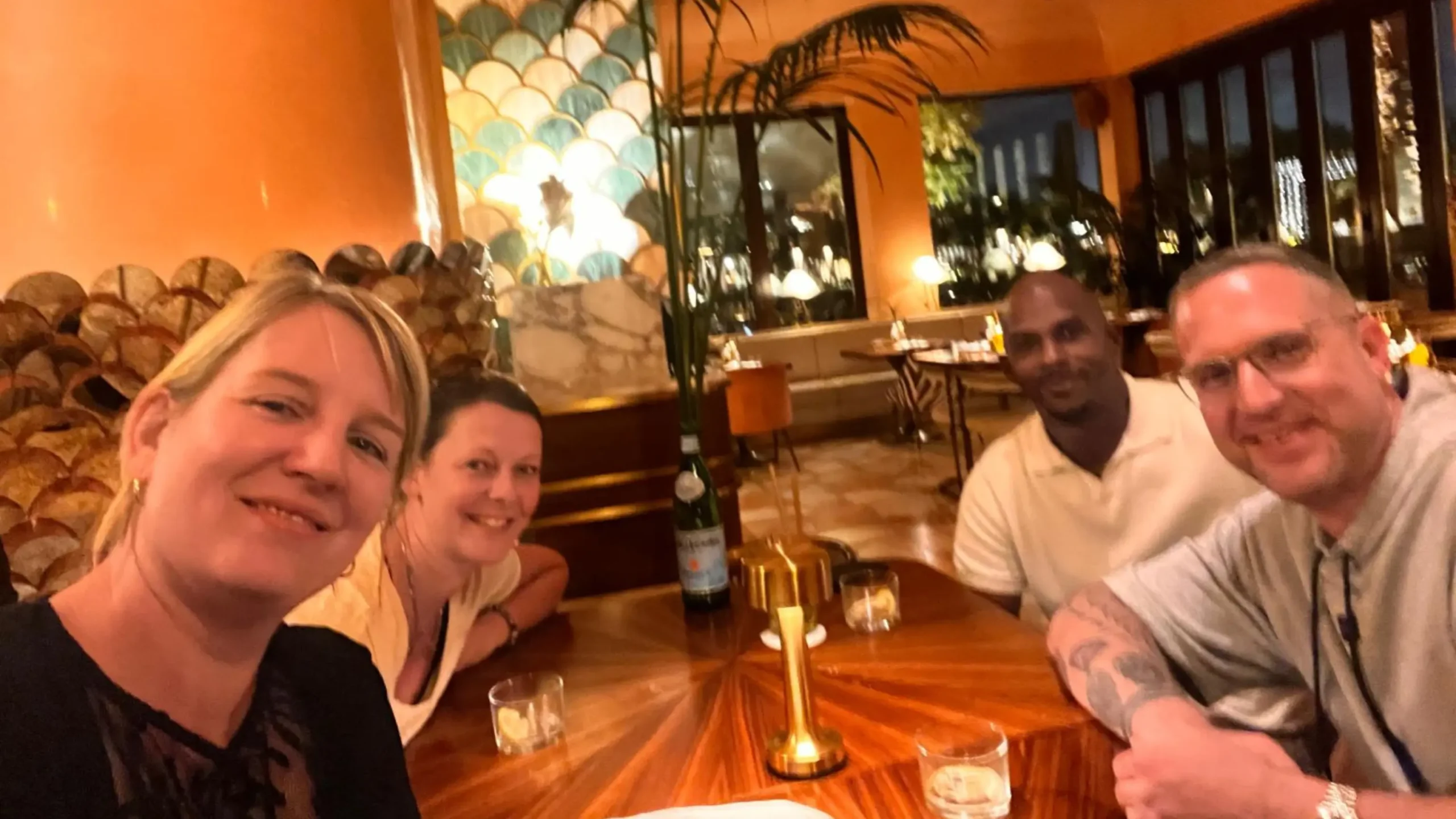 A group of four people smiling at a restaurant table, posing for a selfie. Battle Royal Studios