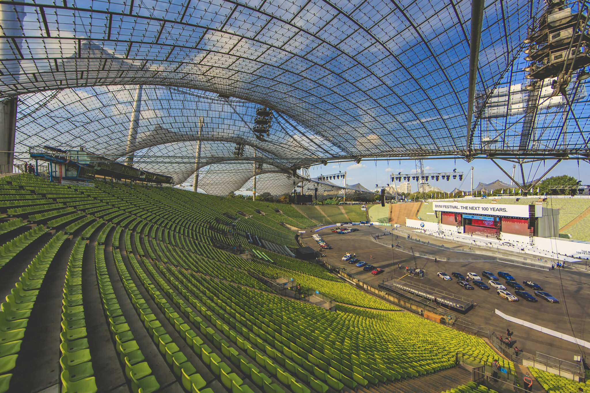 Empty stadium during the setup for the BMW Festival, with the stage and cars in place under a clear blue sky. Battle Royal Studios