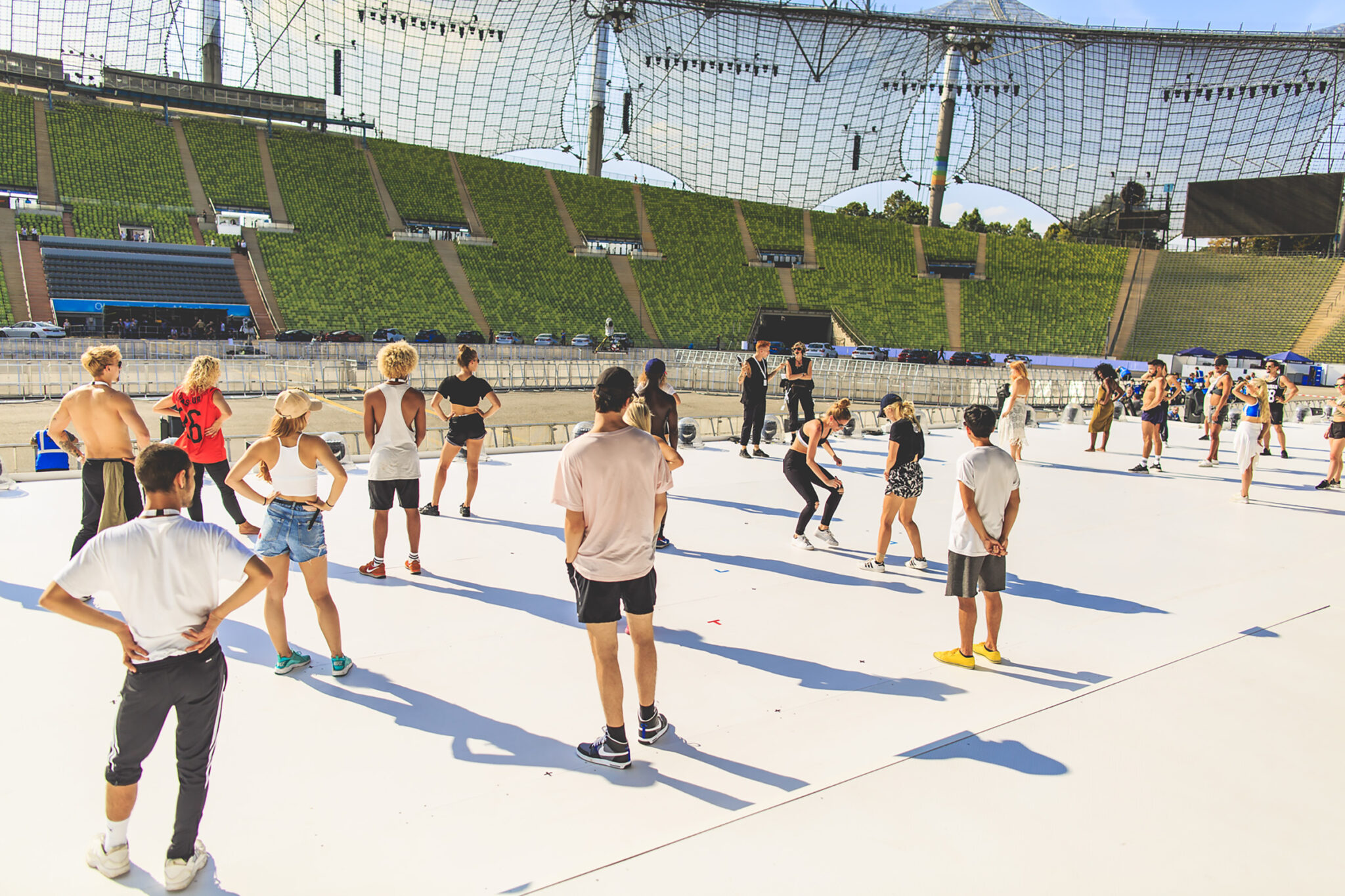 Performers rehearsing on a large stage in an empty stadium during preparations for the BMW Festival. Battle Royal Studios