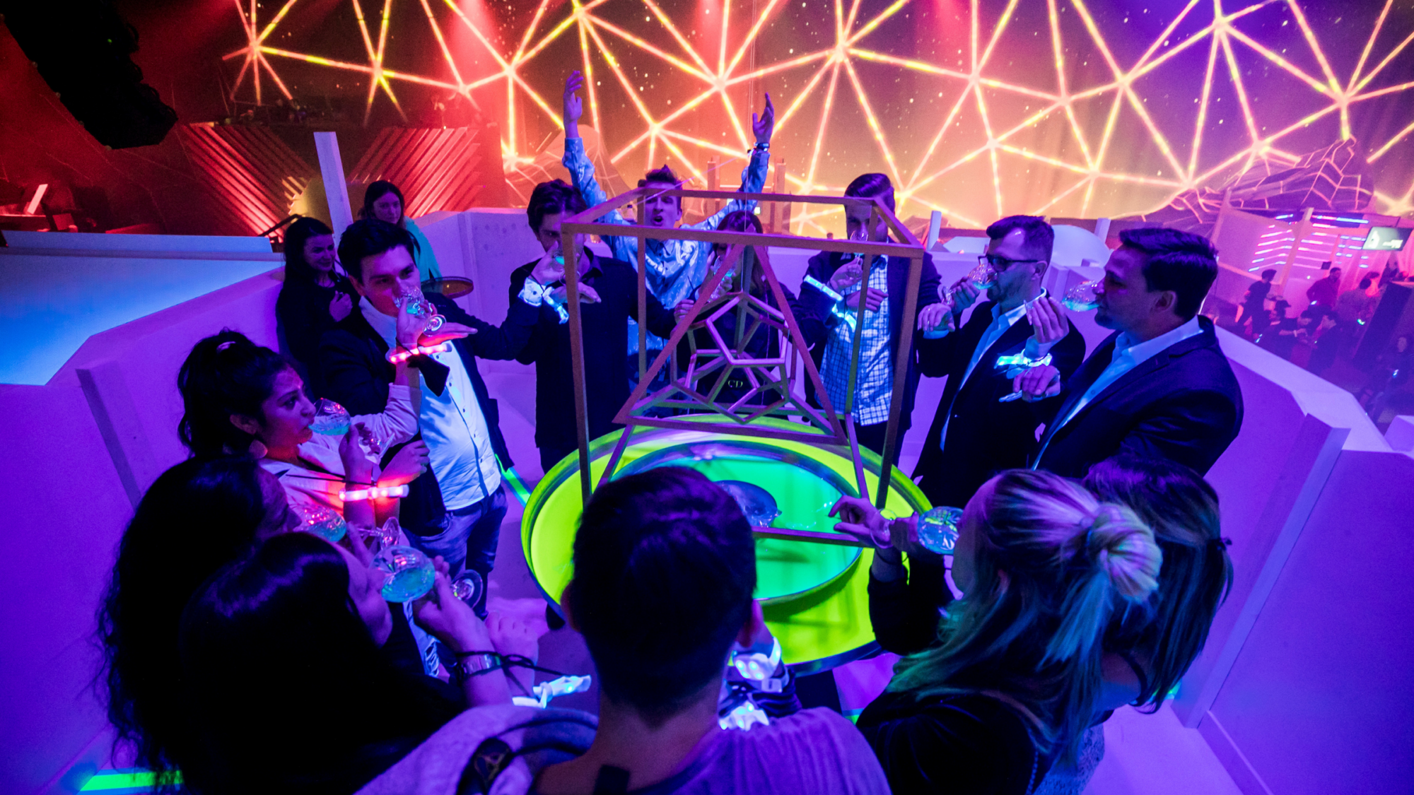 Group of people engaged in an interactive exhibit with neon lights and geometric structures. Battle Royal Studios