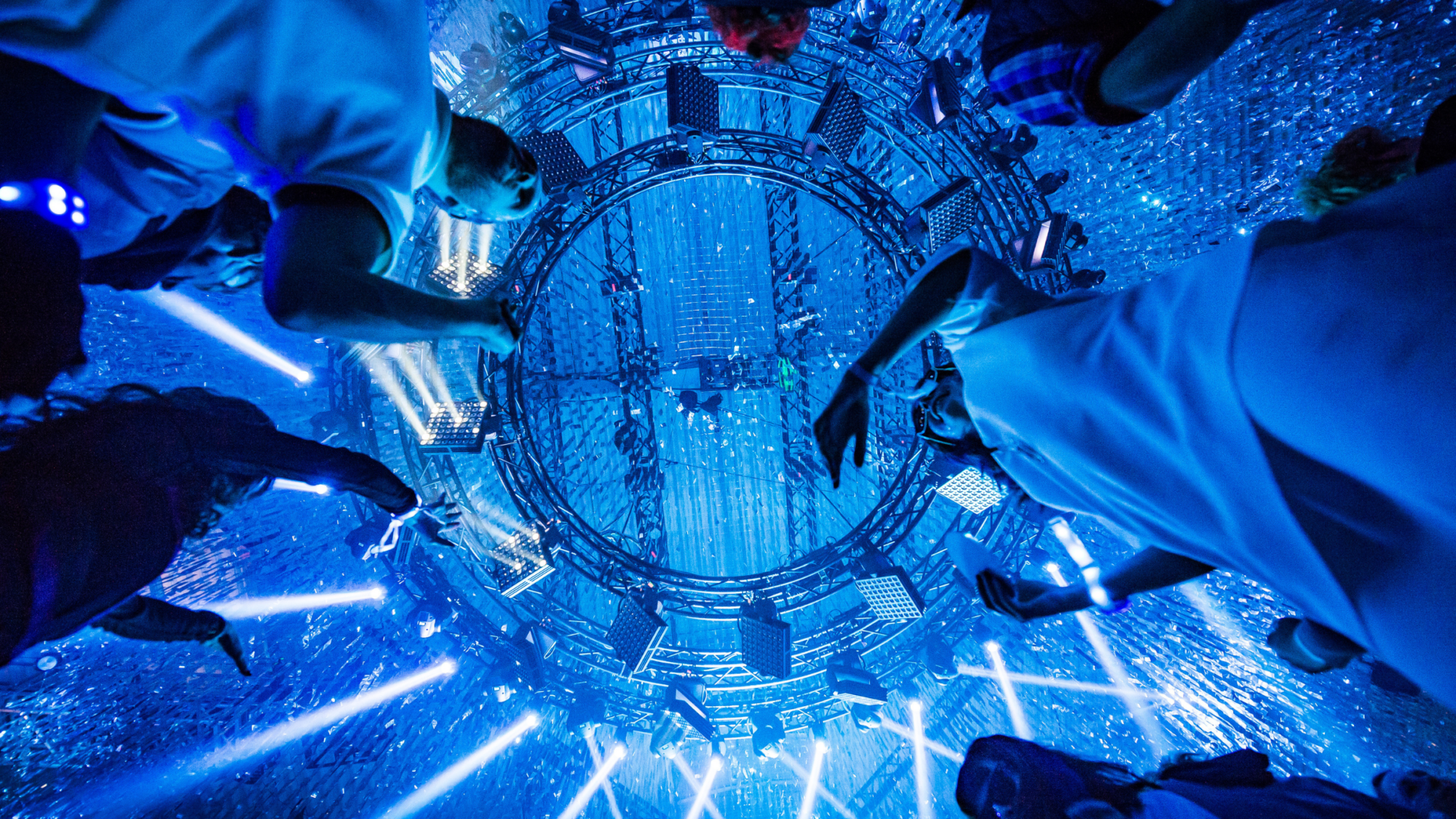 Attendees looking up at a circular stage with dazzling blue lights and visual effects. Battle Royal Studios