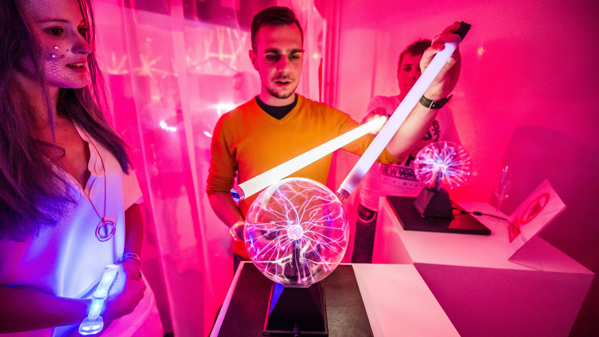 Attendees interacting with a plasma globe in a vibrant, pink-lit room. Battle Royal Studios