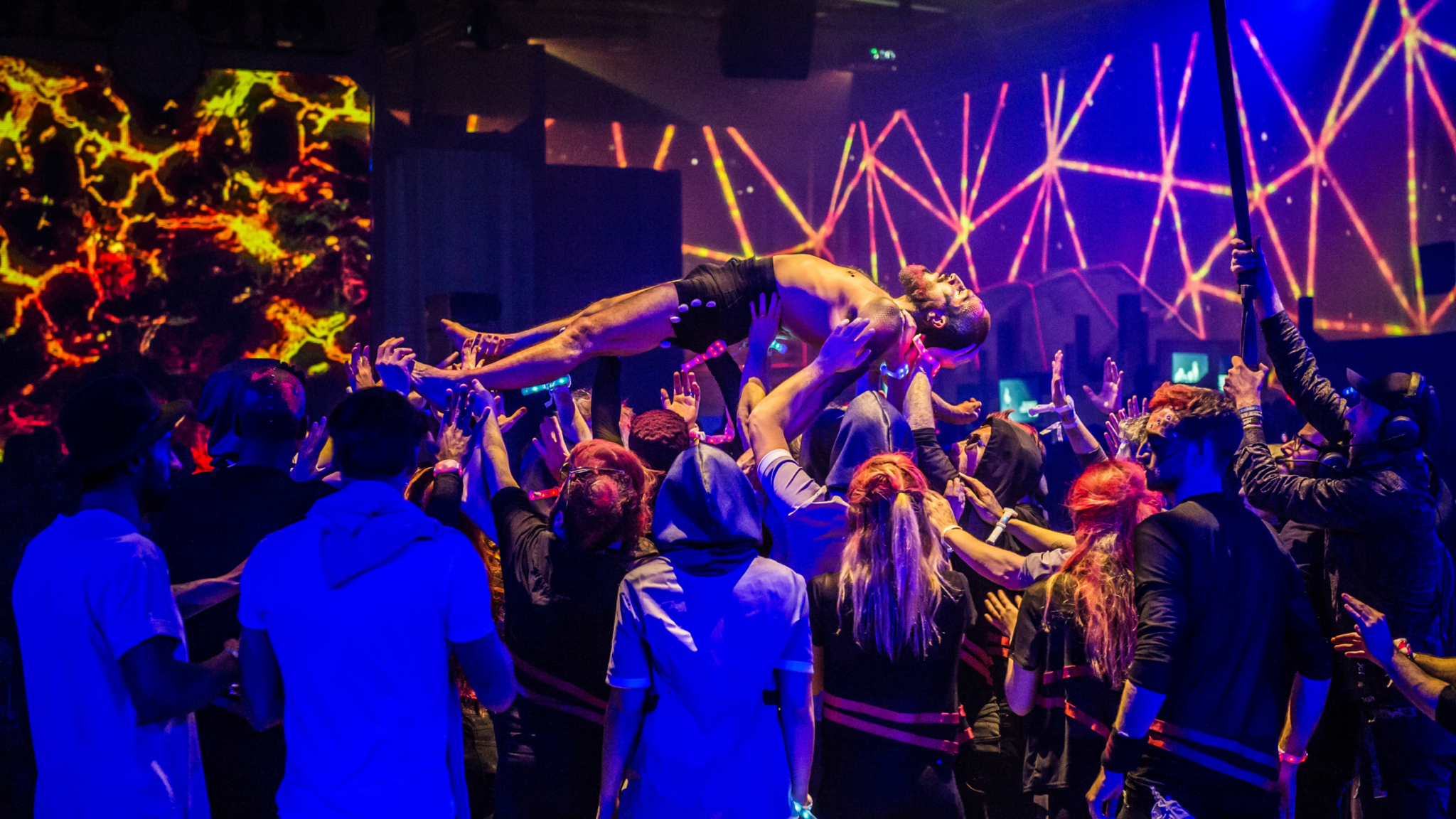 Performer crowd-surfing during a high-energy event at Battle Royal Studios, with vibrant visual effects in the background