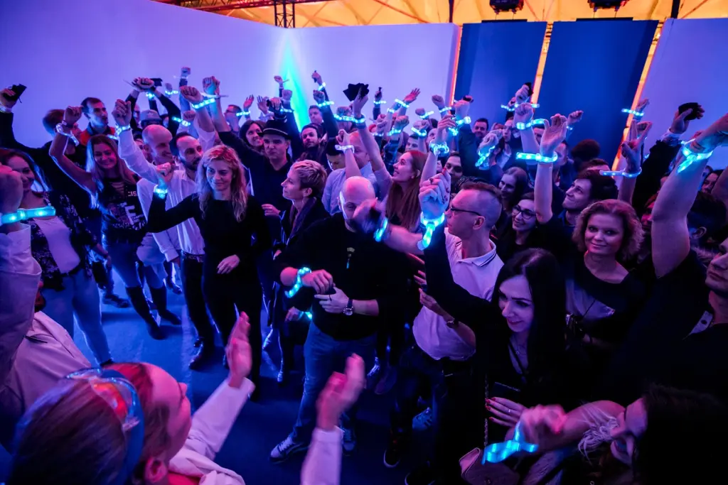 Engaged crowd at a Battle Royal Studios event, wearing illuminated wristbands in a vibrant, blue-lit environment