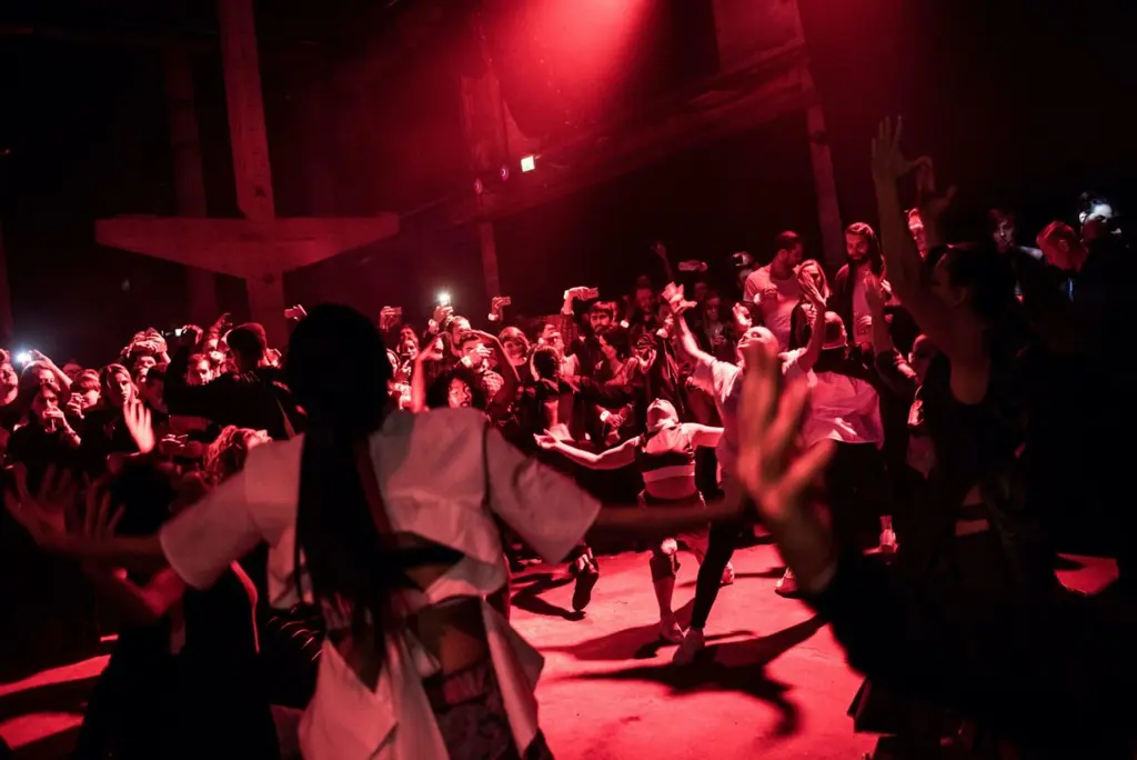 Audience and performers dancing energetically in a red-lit atmosphere. Battle Royal Studios