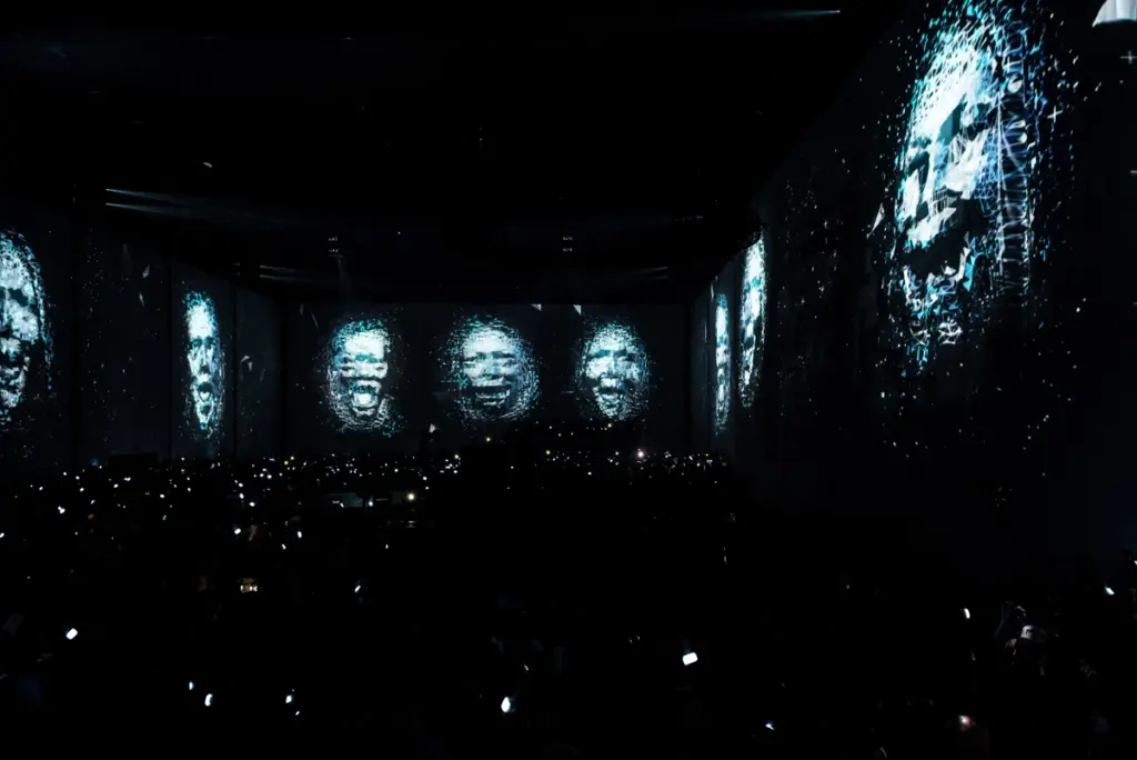 Large-scale digital faces projected on dark screens during an immersive experience. Battle Royal Studios