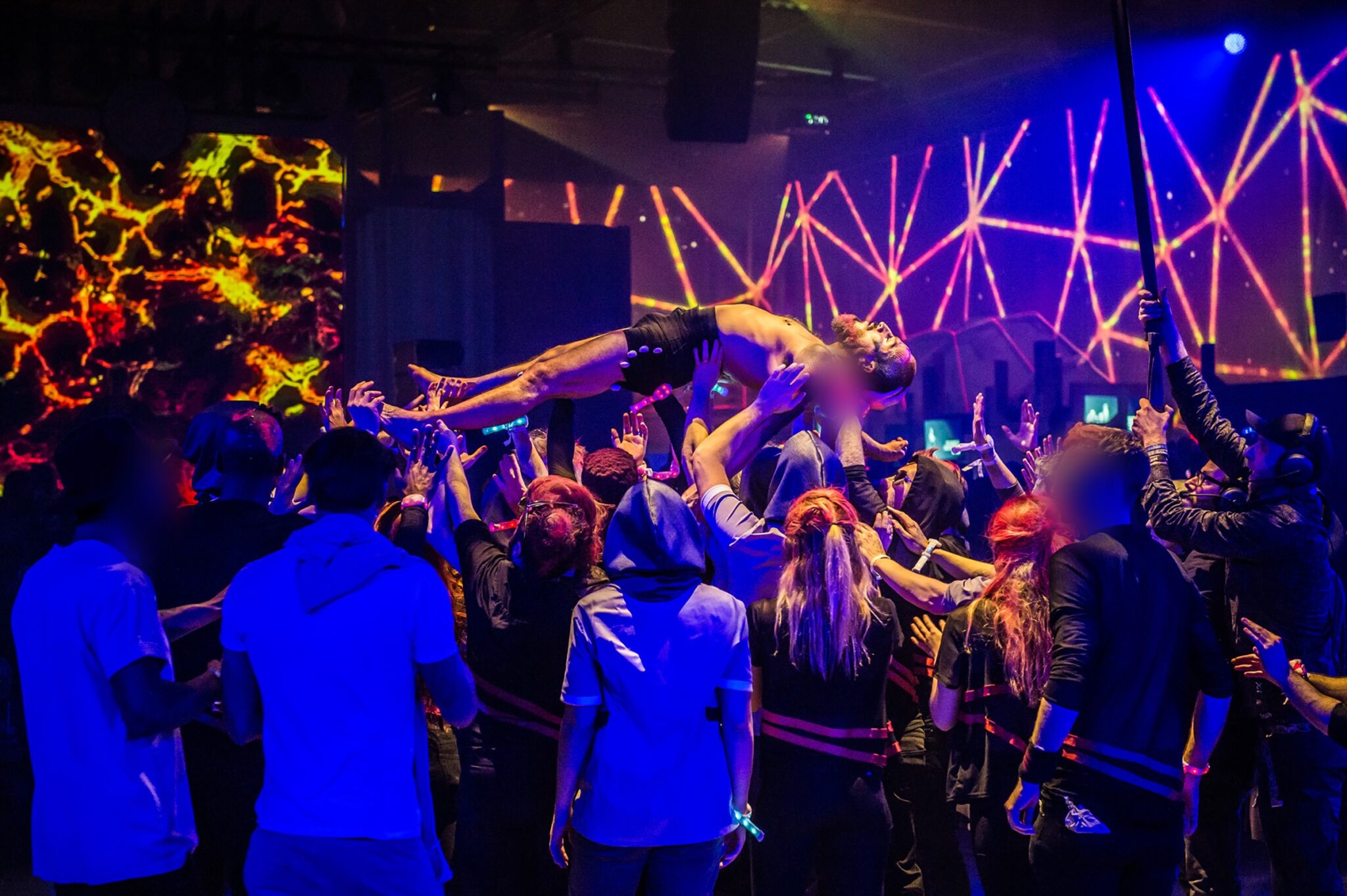 Performer crowd-surfing during a high-energy event at Battle Royal Studios, with vibrant visual effects in the background