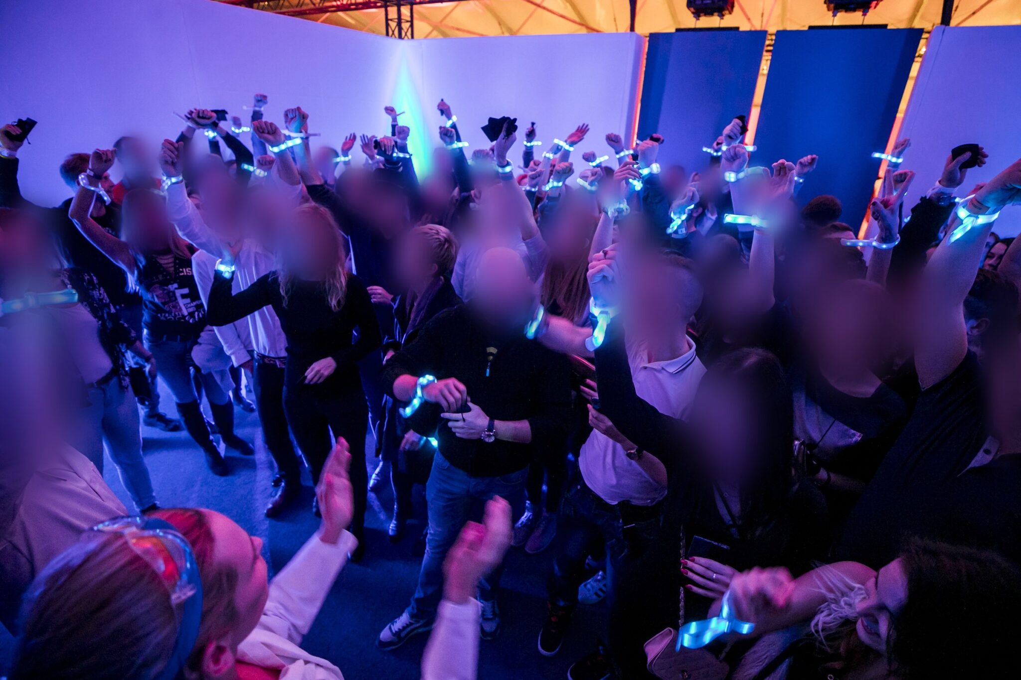 Engaged crowd at a Battle Royal Studios event, wearing illuminated wristbands in a vibrant, blue-lit environment