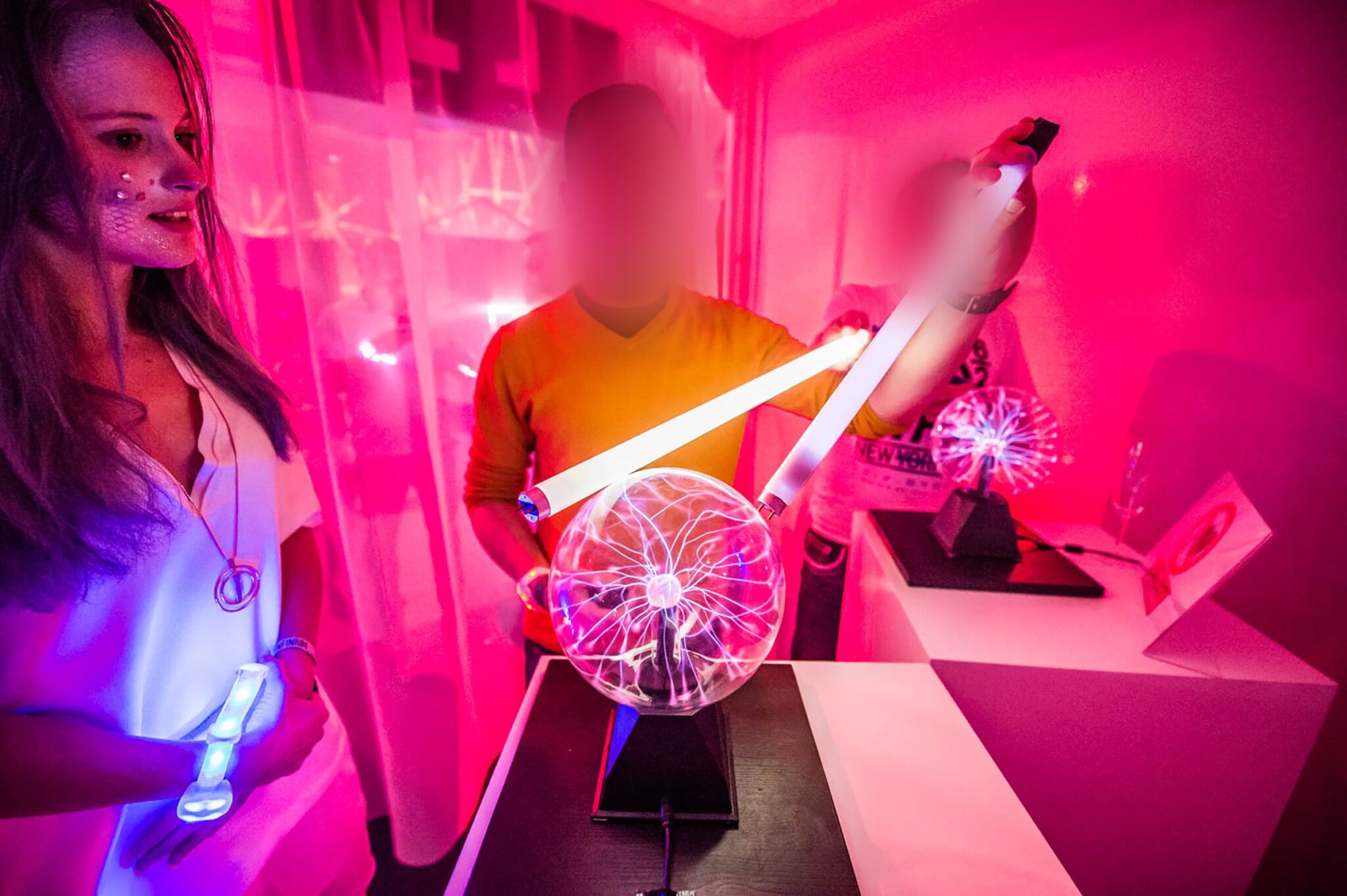 Attendees interacting with a plasma globe in a vibrant, pink-lit room. Battle Royal Studios