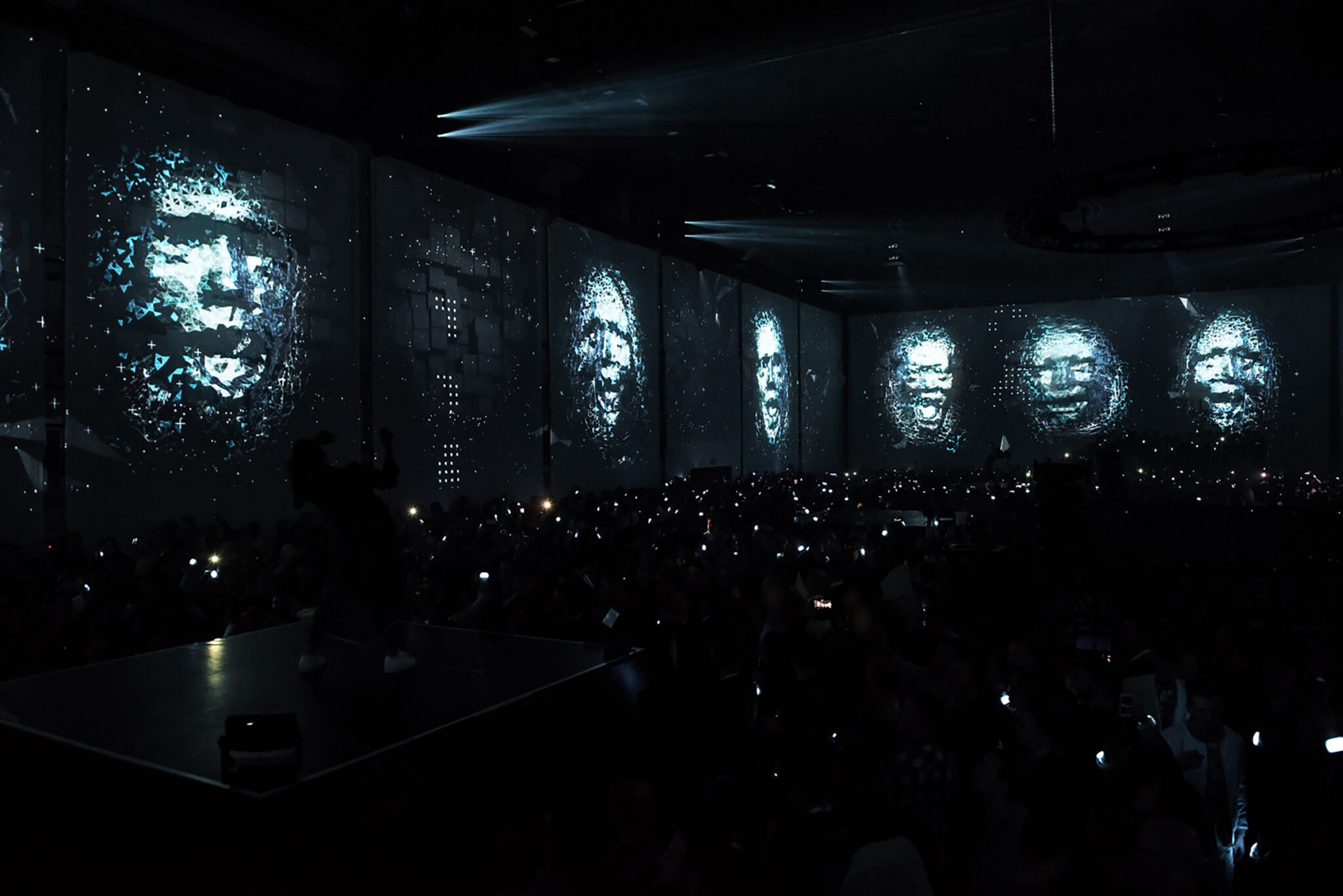 Large-scale digital faces projected on dark screens during an immersive experience. Battle Royal Studios