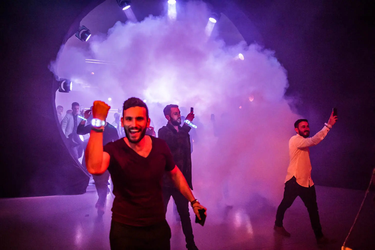 A man excitedly walks through a tunnel filled with smoke, followed by others taking photos in a party atmosphere. BattleRoyalStudios