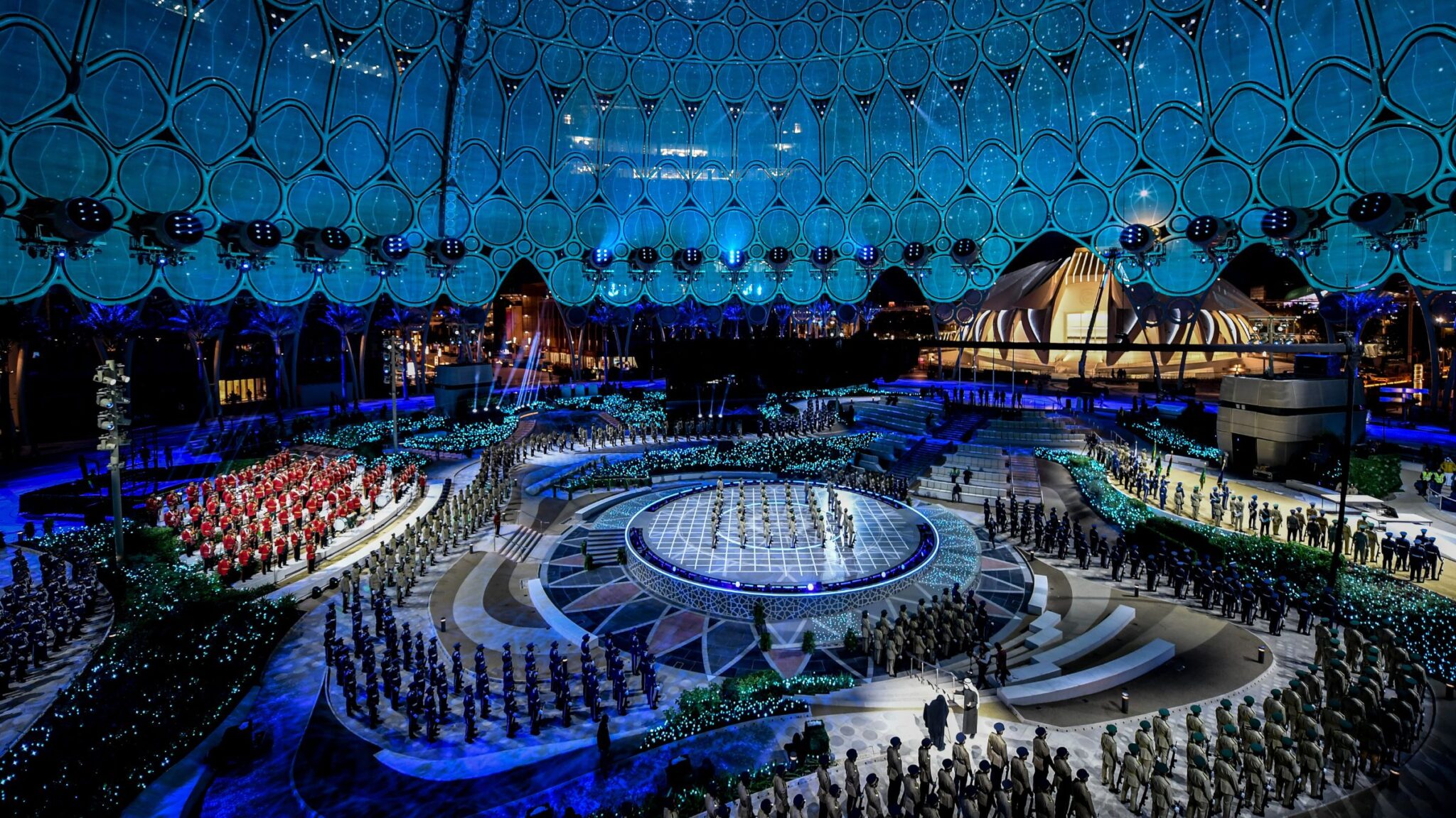 Large outdoor ceremony with uniformed participants in a circular formation under an intricately lit dome. Battle Royal Studios.