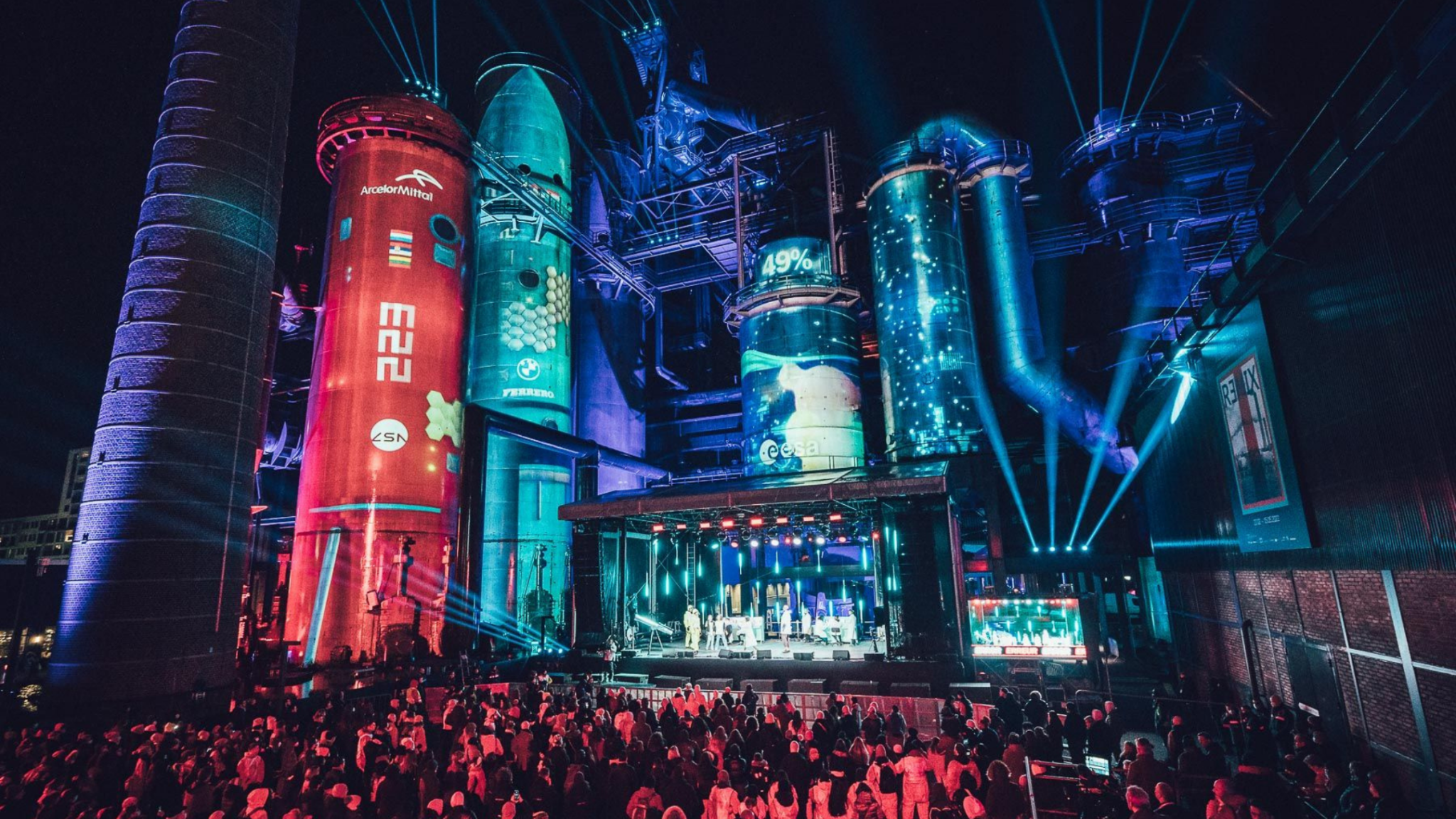 A grand outdoor performance with uniformed groups and a central stage under an illuminated, dome-like structure. Battle Royal Studios