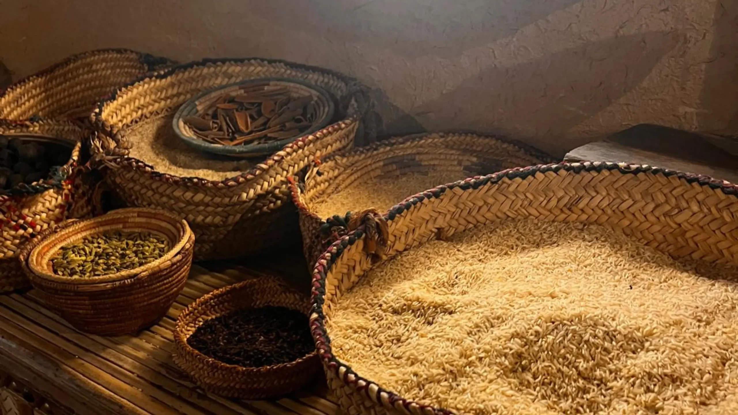 Baskets filled with various spices and grains are displayed on a wooden surface, with soft light illuminating them. Battle Royal Studios