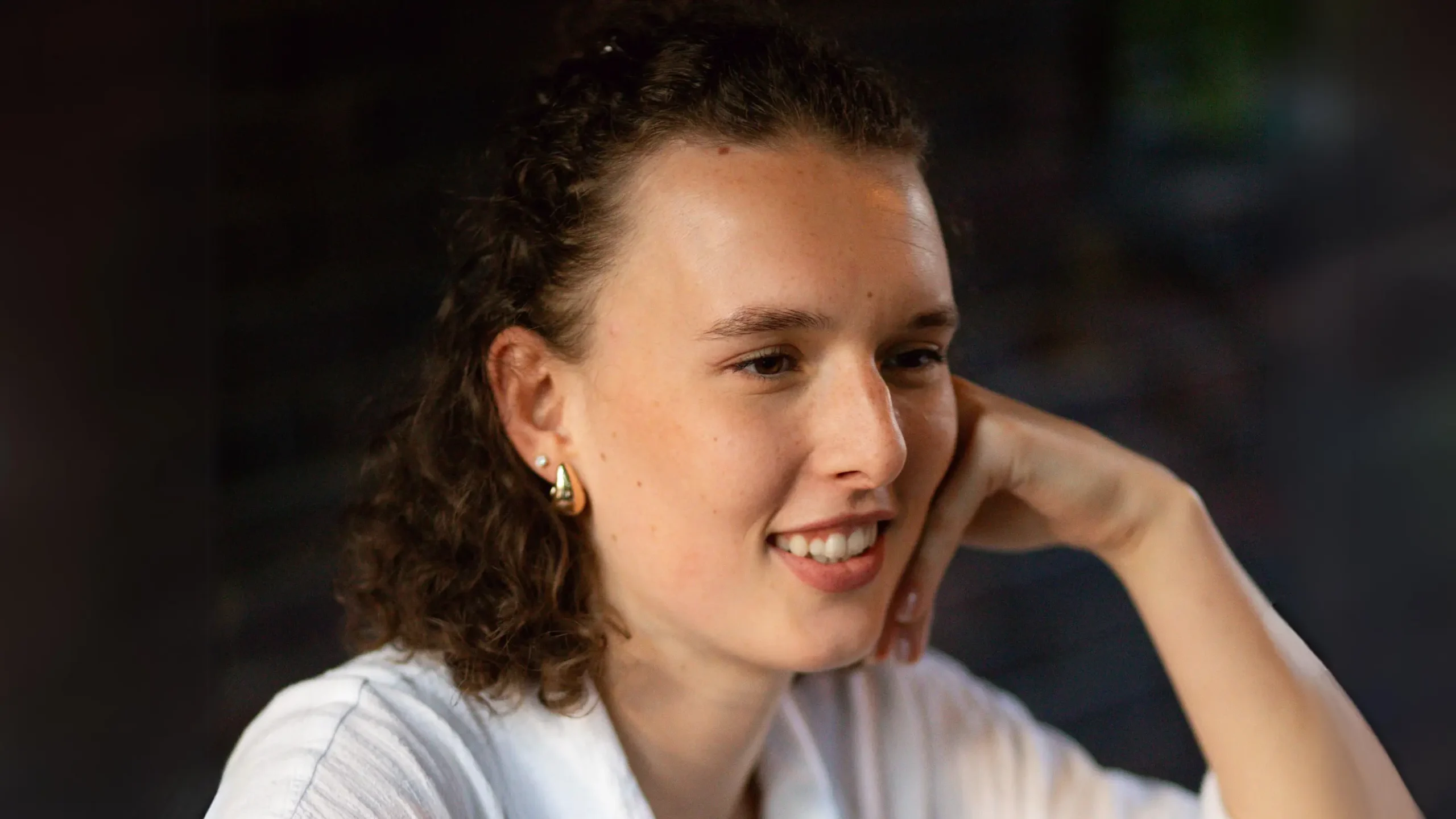 A young woman smiling with her chin resting on her hand