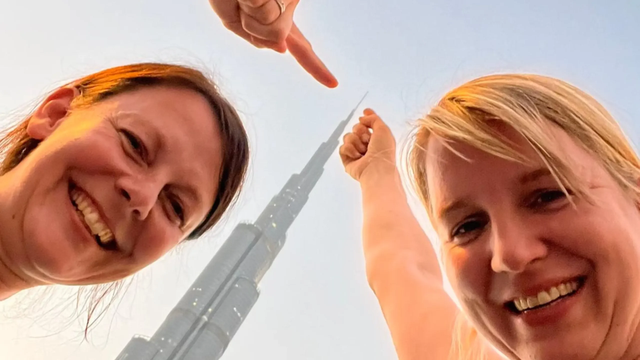 Sarah La Tragna and Judith Hoch smile while pointing up at the Burj Khalifa in the background. Battle Royal Studios