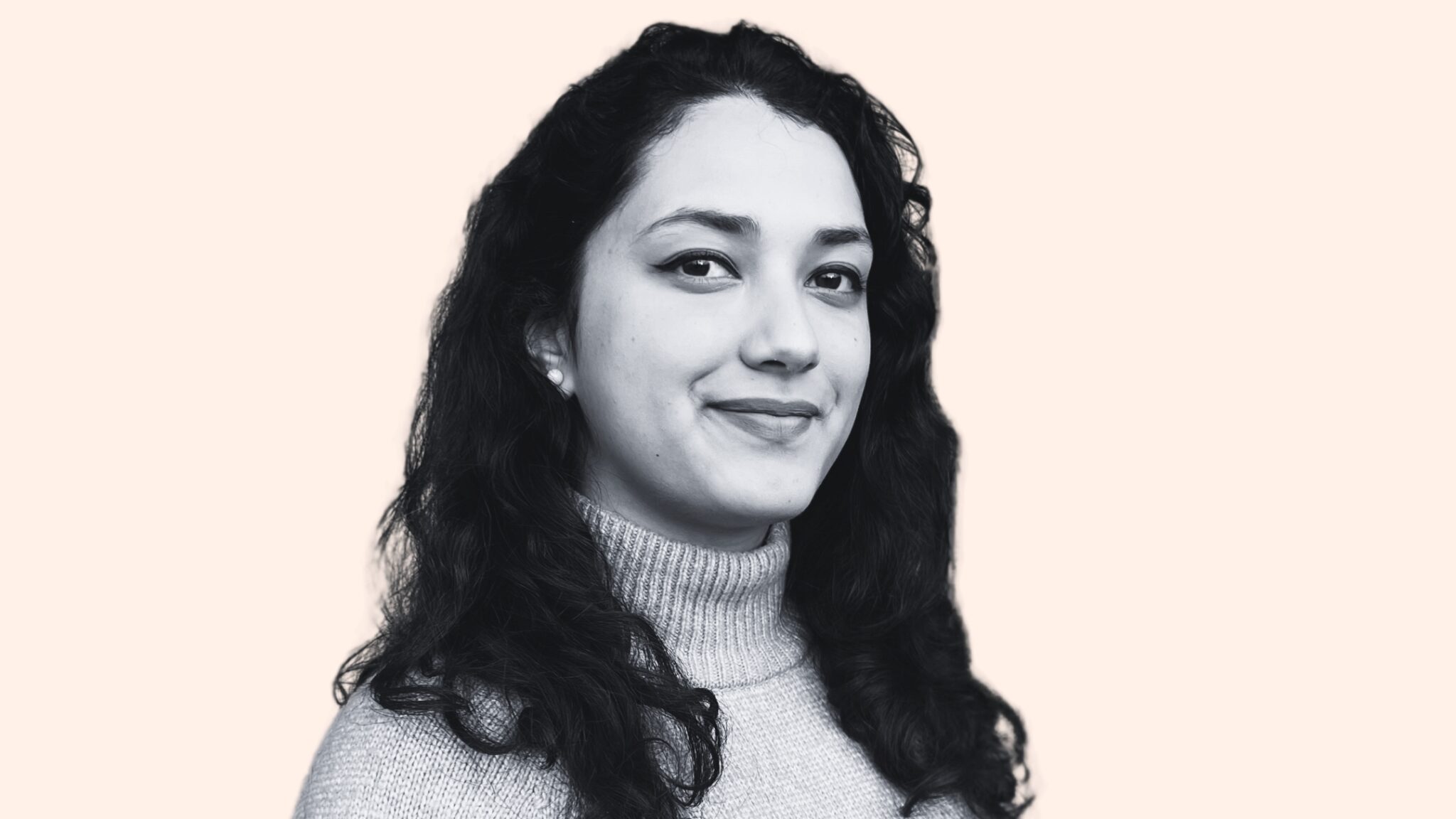 Black and white portrait of a smiling woman with long curly hair on a pale background