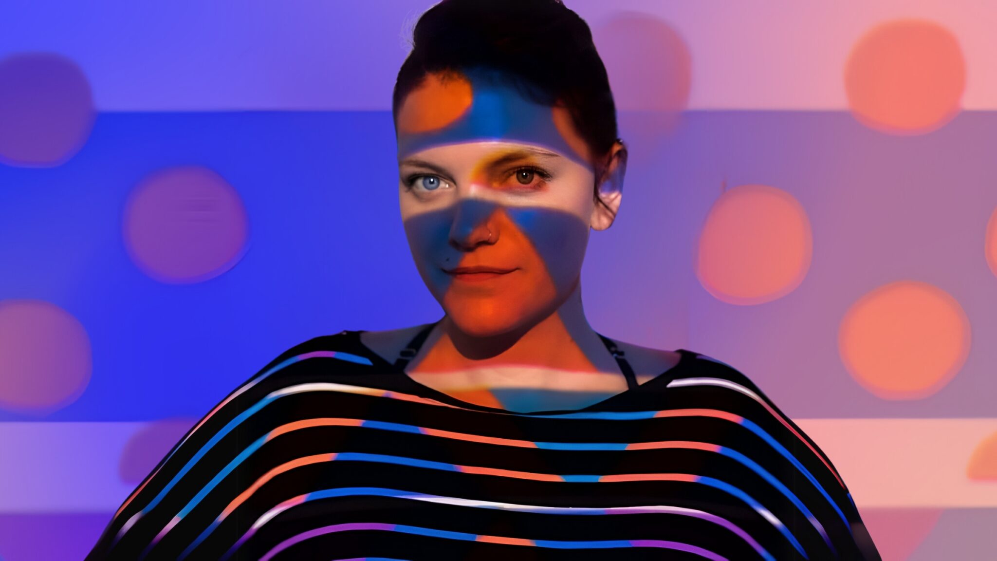 A woman with light patterns projected across her face and striped top