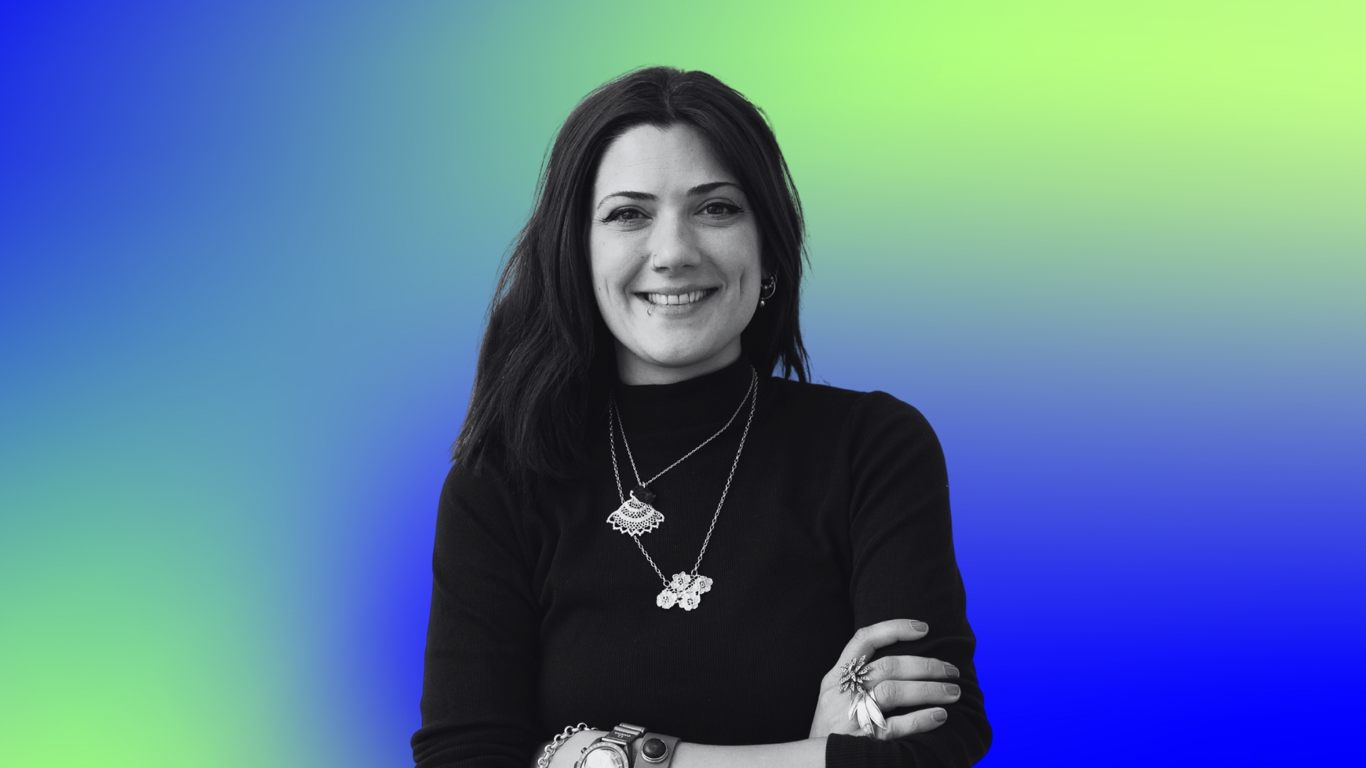Black and white portrait of a smiling woman with arms crossed on a green and blue gradient