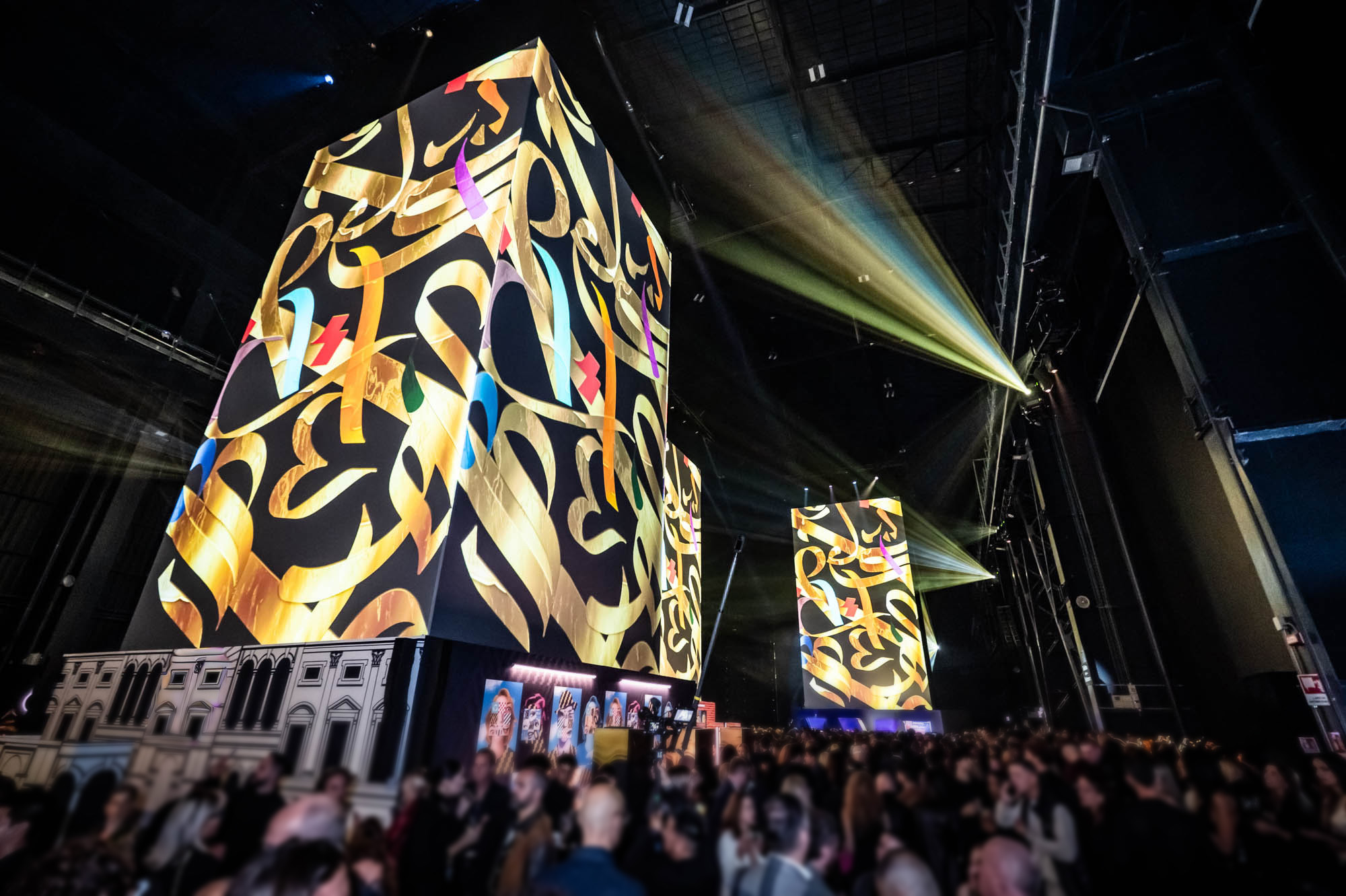 14-metre tower projection-mapped with gold calligraphic artwork above the crowd.