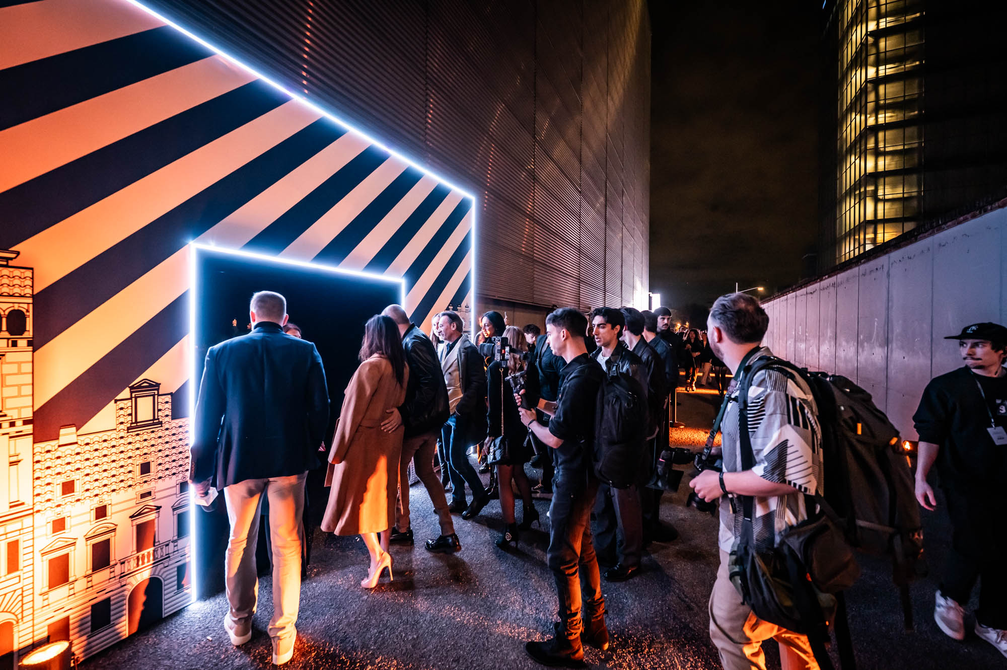 Guests entering through a neon-outlined portal wrapped in bold black and orange stripes.