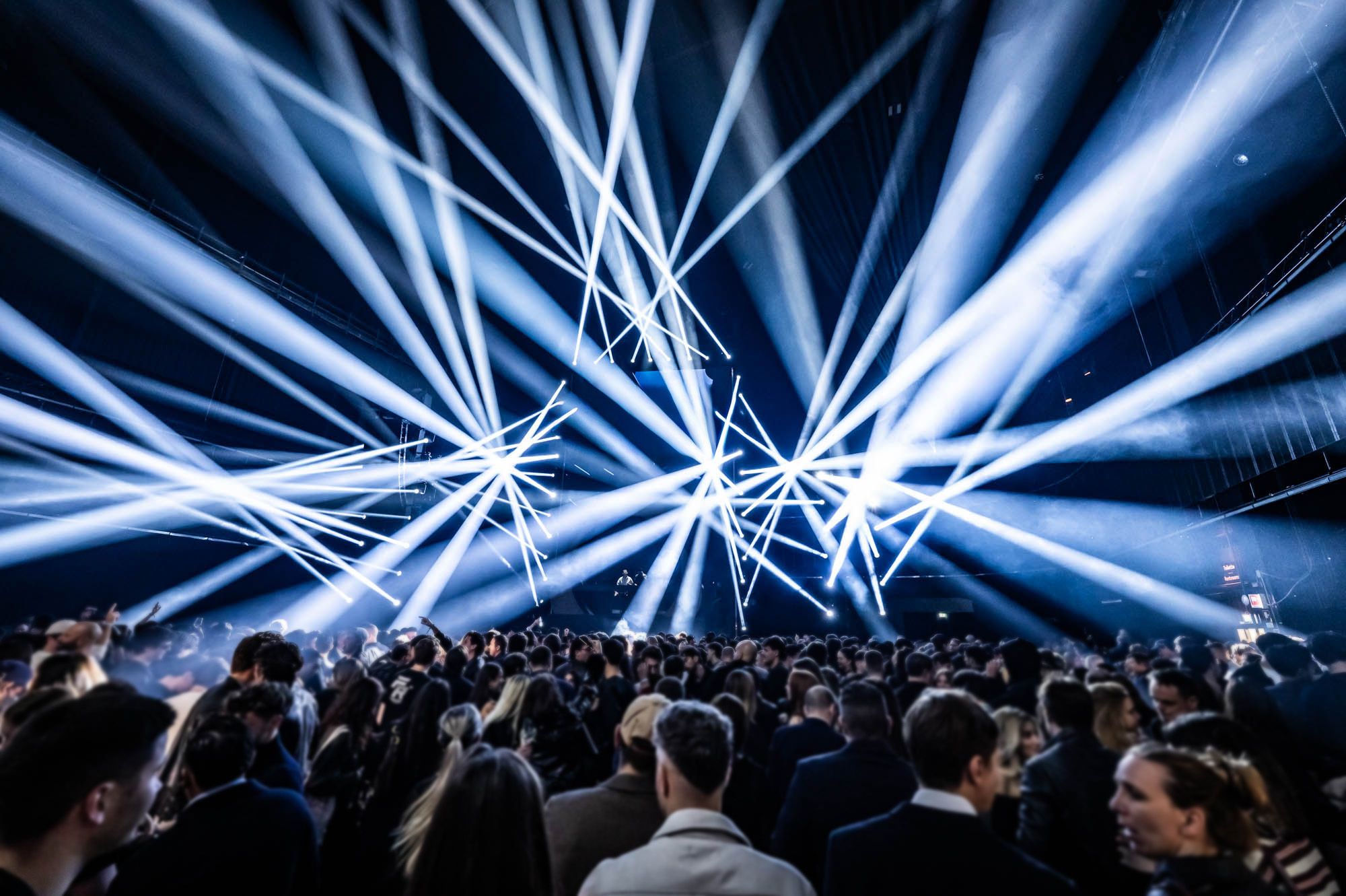 Audience under a dense web of white light beams.