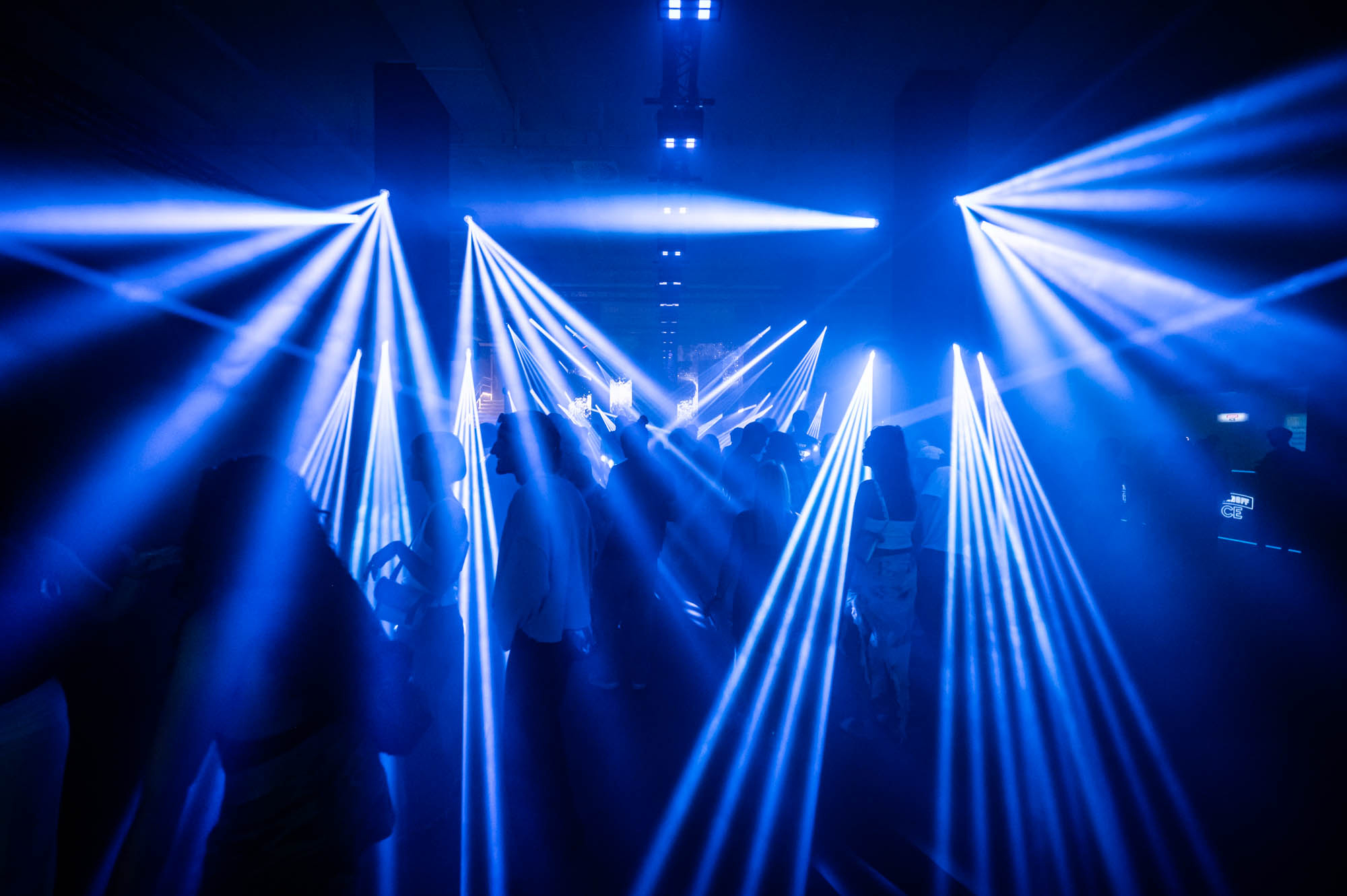 Blue light beams fanning out above a crowd on the Club Duplex dance floor.